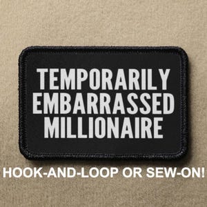 Puede incluir: Parche negro con texto blanco que dice "Temporarily Embarrassed Millionaire". El parche es para sujetar con velcro o coser.