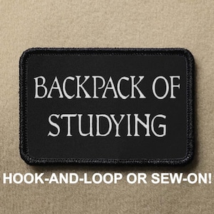 Könnte beinhalten: Schwarzer Patch mit weißem Text, der "BACKPACK OF STUDYING" lautet. Der Patch hat einen schwarzen Rand und wird mit Klettverschluss oder zum Annähen befestigt.