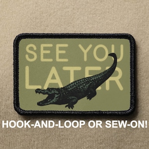 May include: A green and black embroidered patch featuring a black alligator and the text "See You Later" in yellow lettering. The patch is designed for hook-and-loop or sew-on attachment.