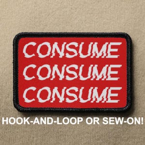 May include: Red iron-on patch with white text that reads "CONSUME CONSUME CONSUME". The patch has a black border and is designed to be sewn or ironed onto clothing.