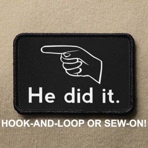 May include: Black and white patch with a pointing hand and the text "He did it." The patch is sewn onto a brown fabric background.