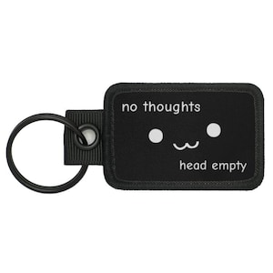 May include: Black keychain with a white rectangle that says "no thoughts head empty" with a simple cartoon face with two eyes and a small smile.