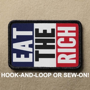 May include: A black, white and red embroidered patch with the text "EAT THE RICH" in white letters. The patch is designed to be attached with hook-and-loop or sewn on.