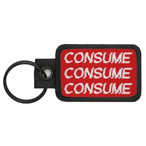 May include: A black and red key chain with a rectangular tag that says "CONSUME" three times in white text.