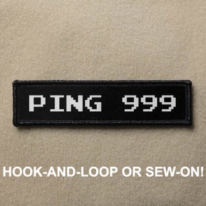 May include: Black patch with white text that reads "PING 999" in a pixelated font. The patch is designed to be attached with hook-and-loop or sewn on.