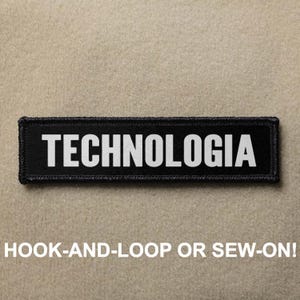 May include: A black rectangular patch with the word "TECHNOLOGIA" in bold white letters. The patch has a black border and the text "HOOK-AND-LOOP OR SEW-ON!" in white below the patch.