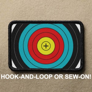 Può includere: Un cerotto per bersaglio di tiro con l'arco bianco e nero con un mirino rosso, giallo e blu. Il cerotto ha un bordo nero e dice "HOOK-AND-LOOP OR SEW-ON!" in basso.