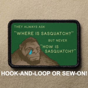 May include: A green and brown embroidered patch featuring a cartoon image of a sad Sasquatch with a single blue tear. The text on the patch reads "They always ask "Where is Sasquatch?" But never "How is Sasquatch?"  The patch is labelled "Hook-and-loop or sew-on!"