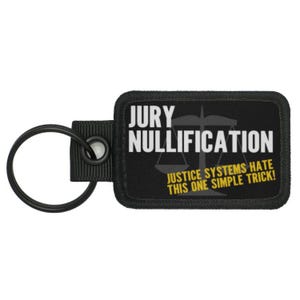 Puede incluir: Llavero negro con un parche negro y blanco que dice "JURY NULLIFICATION" con un gráfico de escala y el texto "JUSTICE SYSTEMS HATE THIS ONE SIMPLE TRICK!"