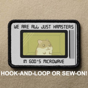 May include: A white and gray embroidered patch with black stitching. The patch features a cartoon hamster in a microwave with the text "We are all just hamsters in God's microwave". The patch is available in hook-and-loop or sew-on options.