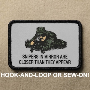 May include: A gray and black embroidered patch with a cartoon image of a sniper aiming a rifle. The text "SNIPERS IN MIRROR ARE CLOSER THAN THEY APPEAR" is printed below the image. The patch is labeled "HOOK-AND-LOOP OR SEW-ON!"