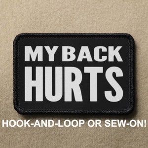 Op de afbeelding: Zwart rechthoekig embleem met de tekst "MY BACK HURTS" in vette witte letters. De patch heeft een zwarte rand en de woorden "HOOK-AND-LOOP OR SEW-ON!" staan eronder gedrukt.