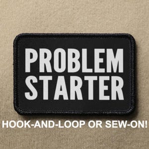 May include: Black patch with white text that reads "PROBLEM STARTER". The patch has a black border and is designed to be attached with hook-and-loop or sewn on.