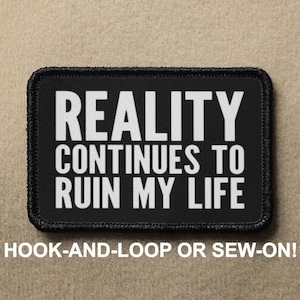 Puede incluir: Parche blanco y negro con el texto "REALITY CONTINUES TO RUIN MY LIFE" en letras blancas. El parche tiene un borde negro y está diseñado para ser fijado con velcro o cosido.