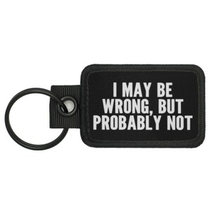 May include: Black rectangular keychain with the text "I MAY BE WRONG, BUT PROBABLY NOT" in white. The keychain has a black metal ring and a black fabric loop.