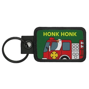 May include: A black and green key chain with a red fire truck and a goose driving. The text "HONK HONK" is printed in yellow on a green background.