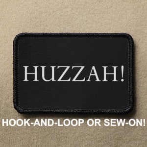May include: Black patch with white text that reads "HUZZAH!"  The patch is for hook-and-loop or sew-on attachment.