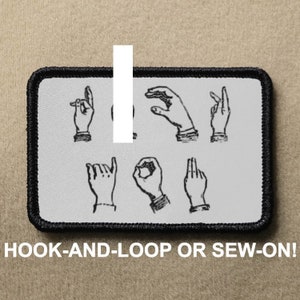 Puede incluir: Un parche blanco con la palabra "I" en texto negro. El parche tiene un borde negro y muestra una serie de manos firmando la palabra "I" en el lenguaje de señas americano. El texto "HOOK-AND-LOOP OR SEW-ON!" está impreso debajo del parche.