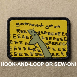 May include: A yellow embroidered patch with black stitching. The patch features a cartoon drawing of a green creature with the text "government get out" and "REEEEEEEEEEE" repeated multiple times.