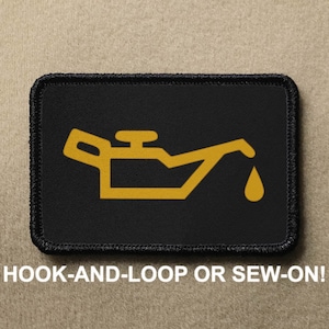 May include: Black patch with a yellow oil can icon and a yellow oil drop. The text "HOOK-AND-LOOP OR SEW-ON!" is below the patch.