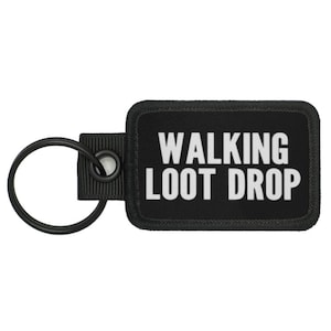 May include: Black rectangular keychain with the text "WALKING LOOT DROP" in white. The keychain has a black metal ring and a black fabric loop.
