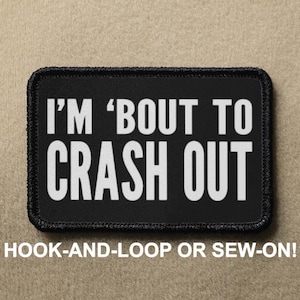 May include: Black rectangular patch with white text reading "I'M 'BOUT TO CRASH OUT." The patch has a black border and the text "HOOK-AND-LOOP OR SEW-ON!" below the main text. The patch is likely for a jacket or bag.