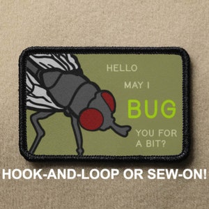 May include: A green and black embroidered patch with a cartoon fly and the text "HELLO MAY I BUG YOU FOR A BIT?"  The patch is designed to be sewn or attached with hook and loop.