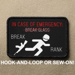 May include: Black and white patch with the text "IN CASE OF EMERGENCY: BREAK GLASS" with a red line through "BREAK GLASS". The patch also shows a stick figure running with a rifle in their hand and the text "BREAK" and "RANK". The patch is labeled "HOOK-AND-LOOP OR SEW-ON!"
