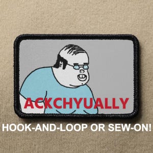 Può includere: Toppa rettangolare con un personaggio dei cartoni animati con occhiali e una maglietta blu. Il testo "ACKCHYUALLY" è in lettere rosse. La toppa ha un bordo nero e il testo "HOOK-AND-LOOP OR SEW-ON!" è sotto.
