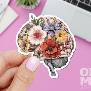 May include: A sticker of a human brain with colorful flowers growing out of it. The brain is a light brown color and the flowers are red, pink, yellow, purple, and green.