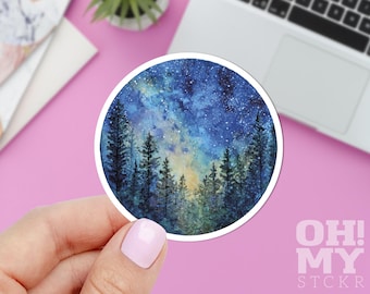 Puede incluir: Una pegatina redonda con una pintura de acuarela de un cielo estrellado sobre un bosque. La pegatina tiene un borde blanco y el texto "OH! MY STCKR" en la esquina inferior derecha. La paleta de colores incluye azules, verdes y amarillos.