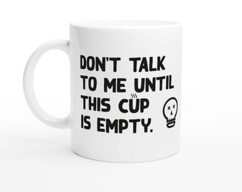 May include: White ceramic coffee mug with black text that reads "Don't talk to me until this cup is empty." A small black and white skull and crossbones graphic is next to the text.