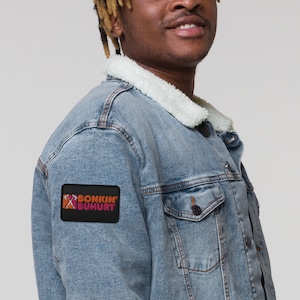 May include: A blue denim jacket with a sherpa collar and a black patch on the left sleeve that says "Bonkin' Buhurt".