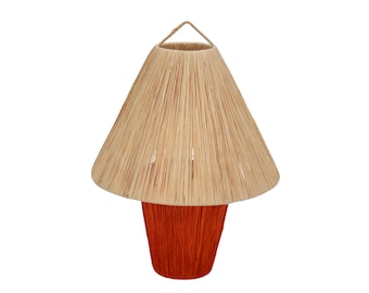 May include: A woven lampshade with a natural beige color and a cone shape. The lampshade is attached to a red woven base.