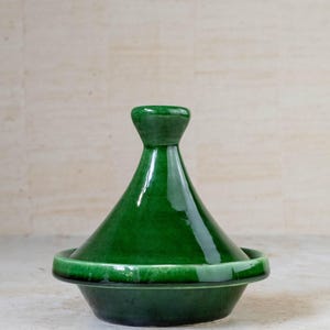 Può includere: Una tagine in ceramica verde con un coperchio conico. La tagine è una pentola da cucina tradizionale marocchina.