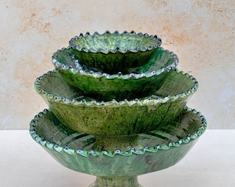 Puede incluir: Juego de cuatro cuencos de cerámica verde, apilados sobre un pedestal. Los cuencos tienen un borde con volantes y un acabado texturizado y esmaltado. El color es un verde vibrante y moteado. Ideal para servir alimentos.