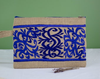 May include: A blue and brown jute clutch bag with a zipper closure and a blue embroidered floral design.
