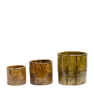 May include: Three ceramic pots of varying sizes, all with a rustic, earthy glaze. The largest pot is a deep green with brown streaks, while the smaller pots are a lighter brown with green accents.