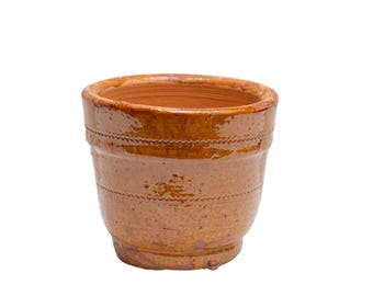 Puede incluir: Una maceta de terracota marrón con un acabado esmaltado. La maceta tiene una forma ligeramente redondeada y una abertura ancha.