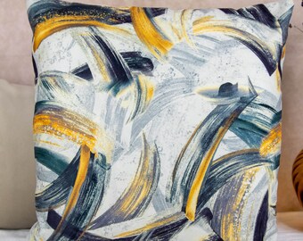 Könnte beinhalten: Ein quadratisches Kissen mit einem abstrakten Design mit gelben, blauen und schwarzen Pinselstrichen auf weißem Hintergrund.