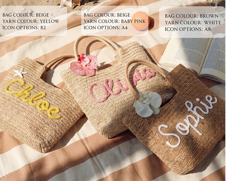May include: Three woven straw tote bags with embroidered names: "Chloe" in yellow, "Olivia" in baby pink, and "Sophie" in white. Each bag has a wooden handle and is decorated with a flower. The bags are on a striped surface.