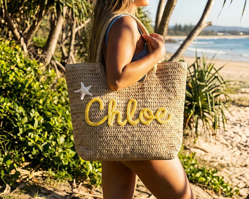 May include: A beige woven tote bag with the name "Chloe" in yellow script. A white starfish is attached to the bag. The bag has a rectangular shape and is being held by a person.