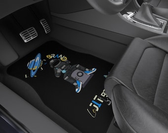 May include: Black car floor mats featuring a cartoon astronaut with a camera, a planet, and the word "BRAND". The astronaut is wearing a space suit and blue sneakers. The mats are designed to protect the car's interior.