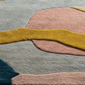 Modern artistic area rug in mustard, teal, pink, and neutral tones