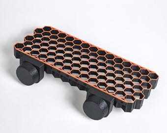 May include: A black honeycomb-shaped platform with orange accents and two black wheels on each side.