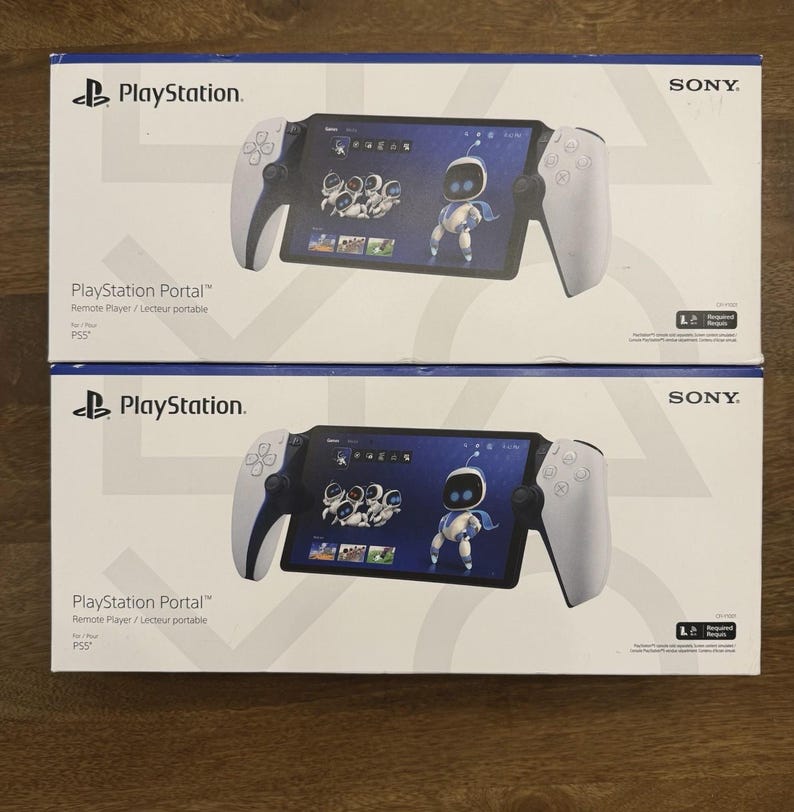 May include: Two white and blue PlayStation Portal boxes are stacked on a wooden surface. Each box features the PlayStation logo, the product name, and a graphic of the device displaying a character. The Sony logo is visible on the top right corner.