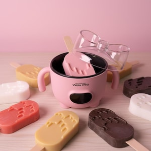May include: A pink Professional Wax Pro wax warmer with two side handles and a black digital display. A clear plastic lid sits partially open on top. Several popsicle-shaped wax bars in various colors including brown, tan, white, and red surround it.