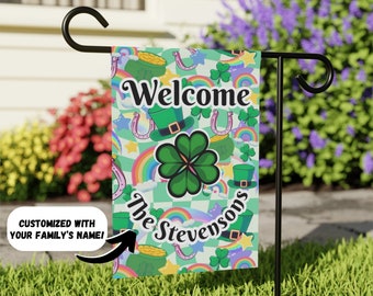 Może przedstawiać: Zielona flaga ogrodowa z napisem "Welcome The Stevensons", koniczyną, tęczami i złotymi monetami.
