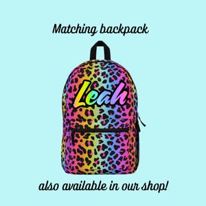 May include: A rainbow leopard print backpack with the name "Leah" in a rainbow font.