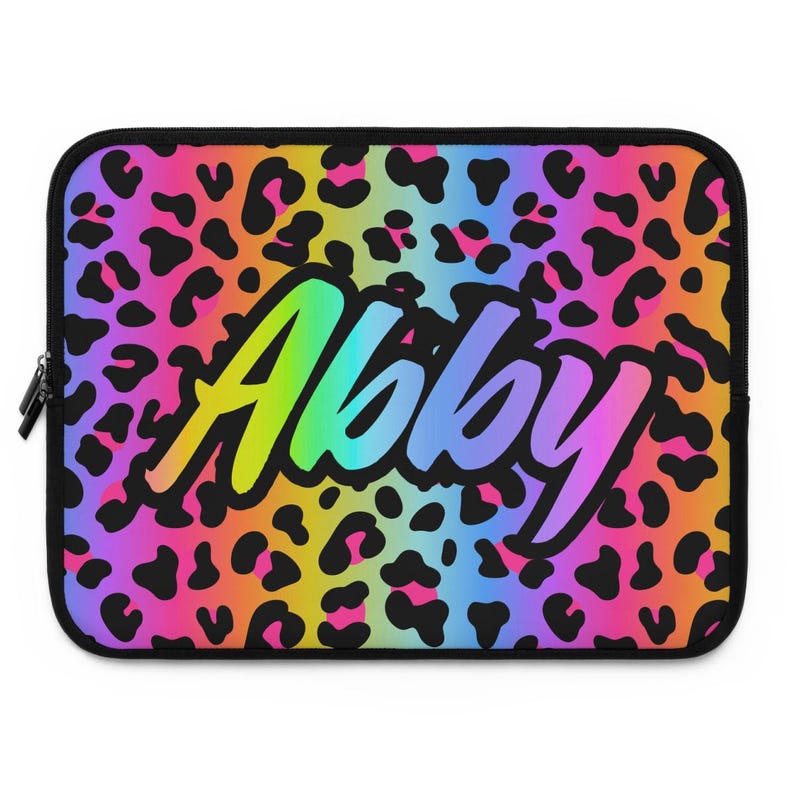 May include: A laptop sleeve with a black leopard print background and a rainbow gradient overlay. The name "Abby" is written in a rainbow gradient font across the center of the sleeve.